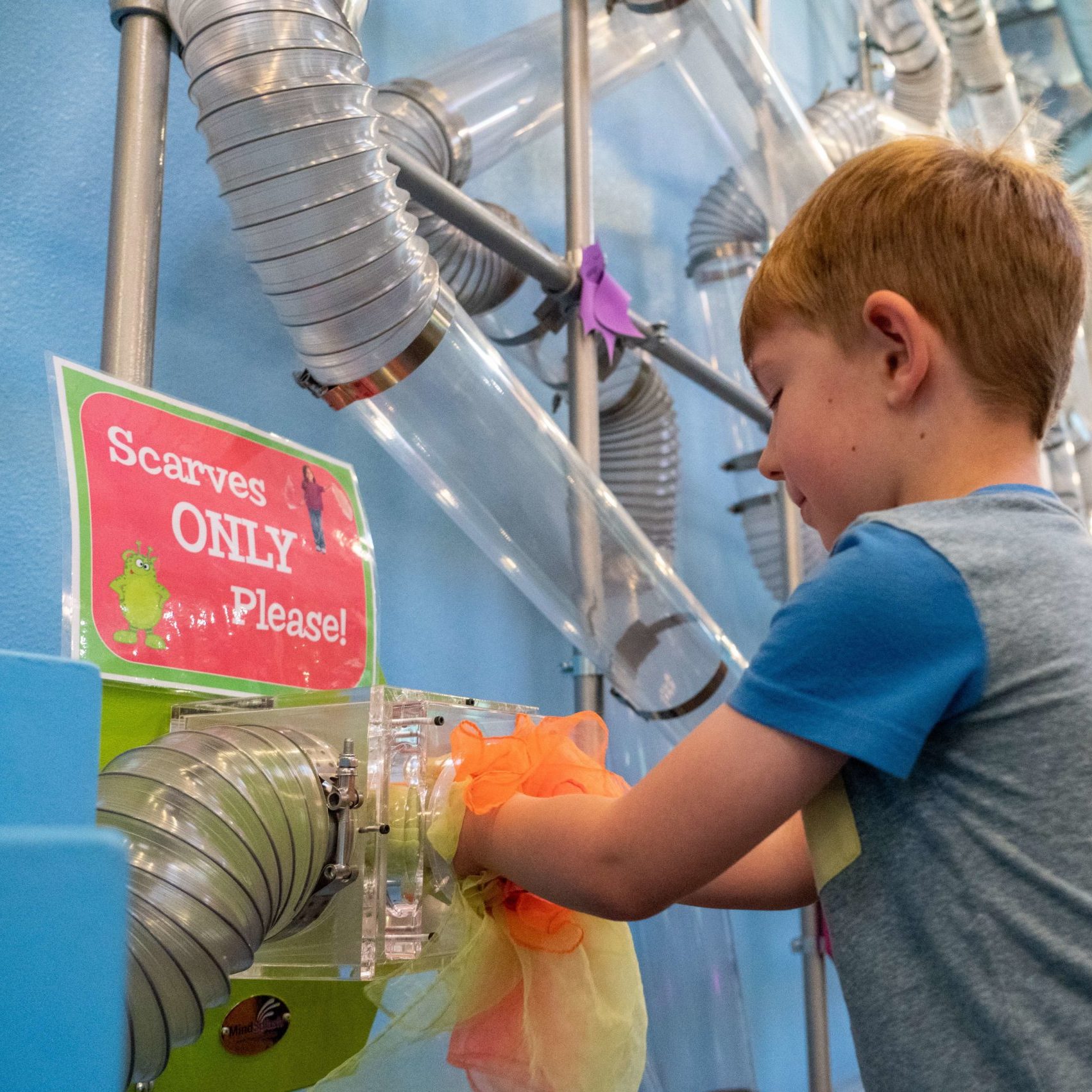 A boy pushes scarves into our wind chute as part of Airways!