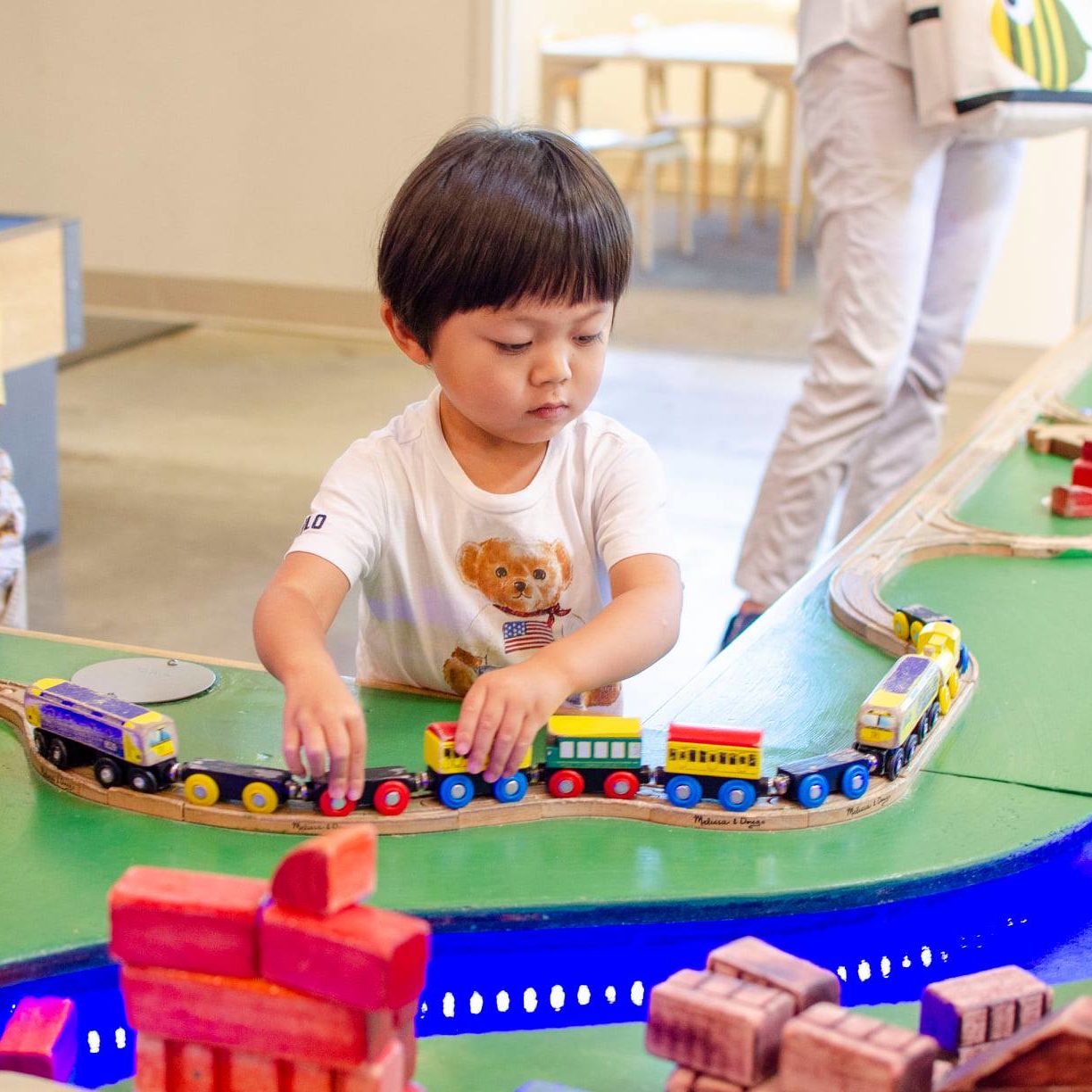 A boy is shown playing with a train on our train table