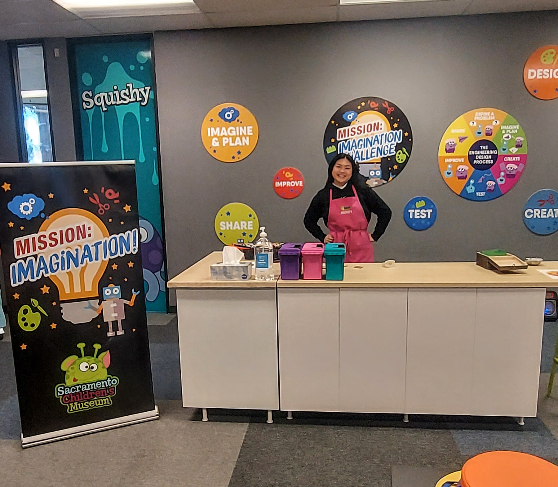 A girl standing behind a counter full of boxes with challenges for guests