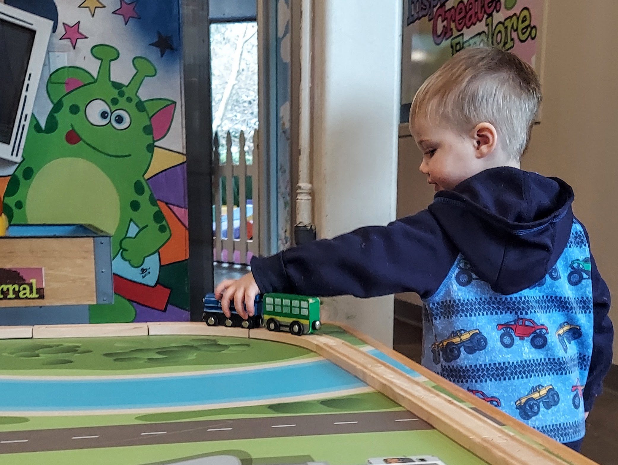 A boy plays with a toy train on a train table