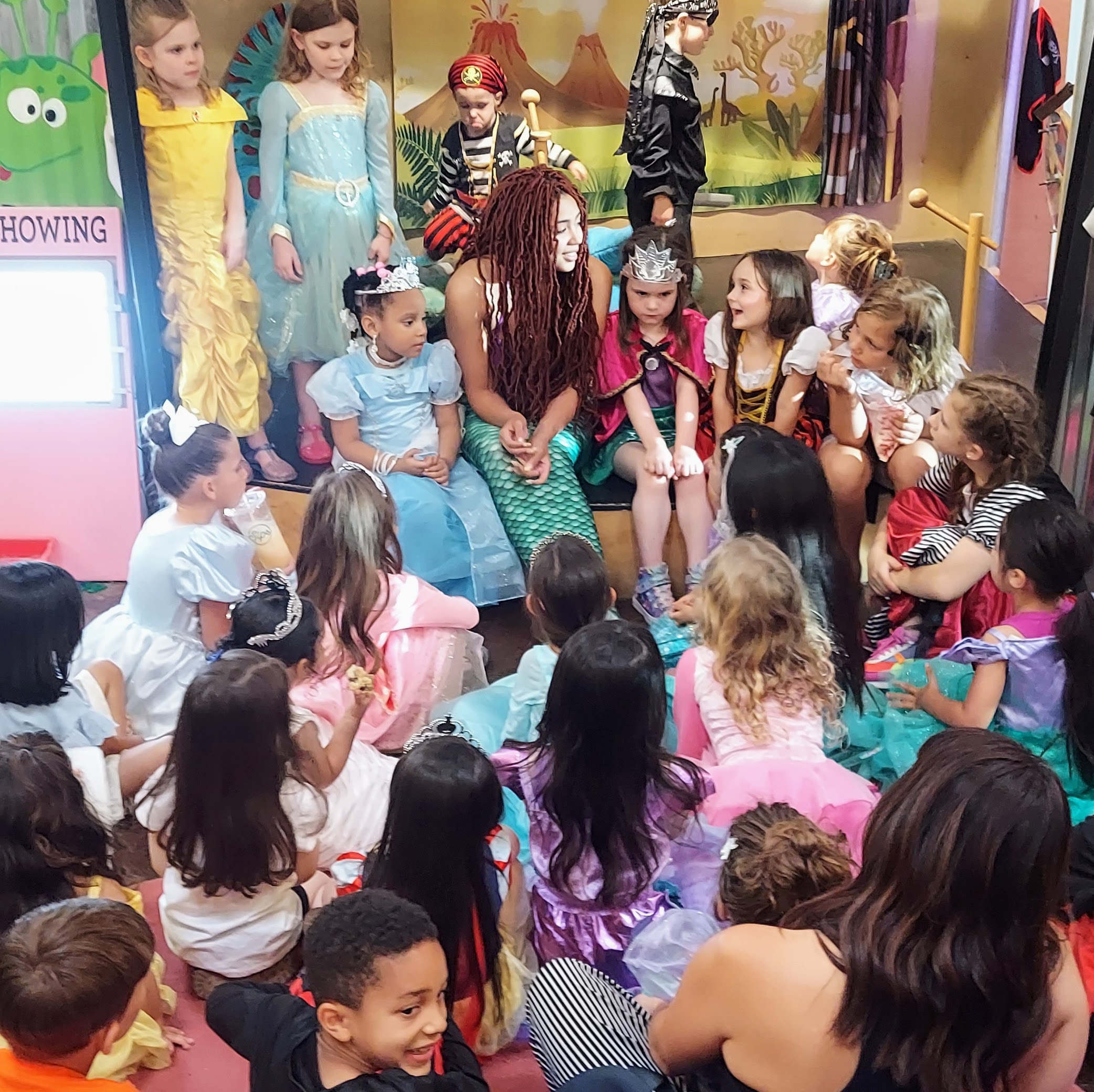A large group of children surround a woman dressed as a mermaid