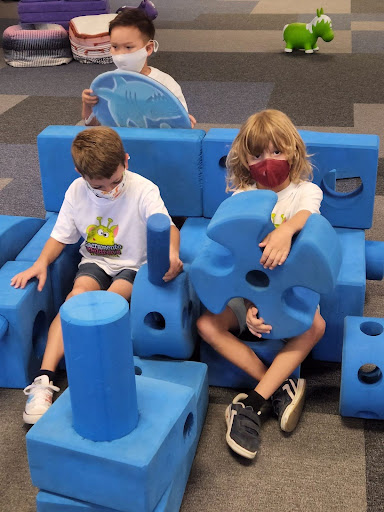 Three children play with big blue blocks