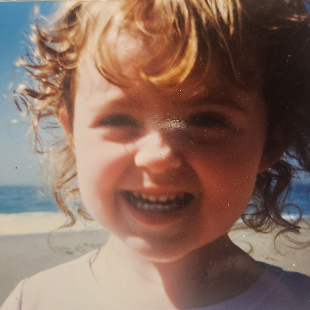 A child looks into the camera, smiling